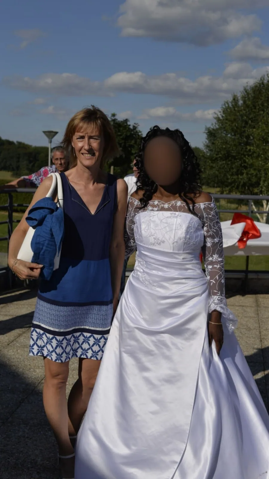 La mariée en blanc et son invitée en bleu, en extérieur