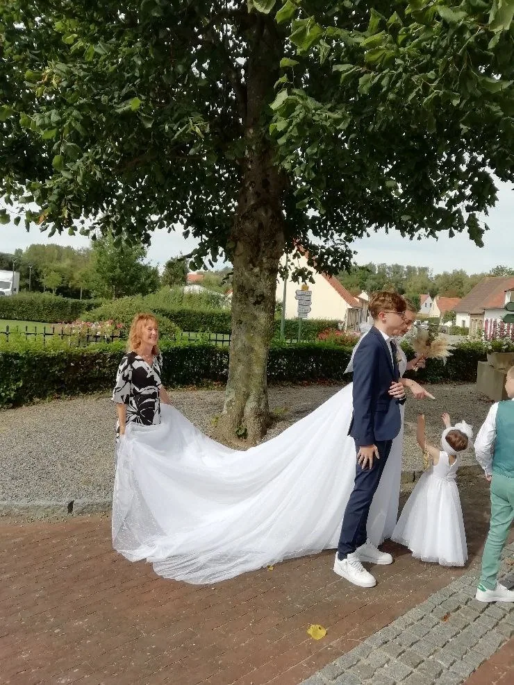 Les mariés et les enfants tenant la traîne de la robe sous un arbre