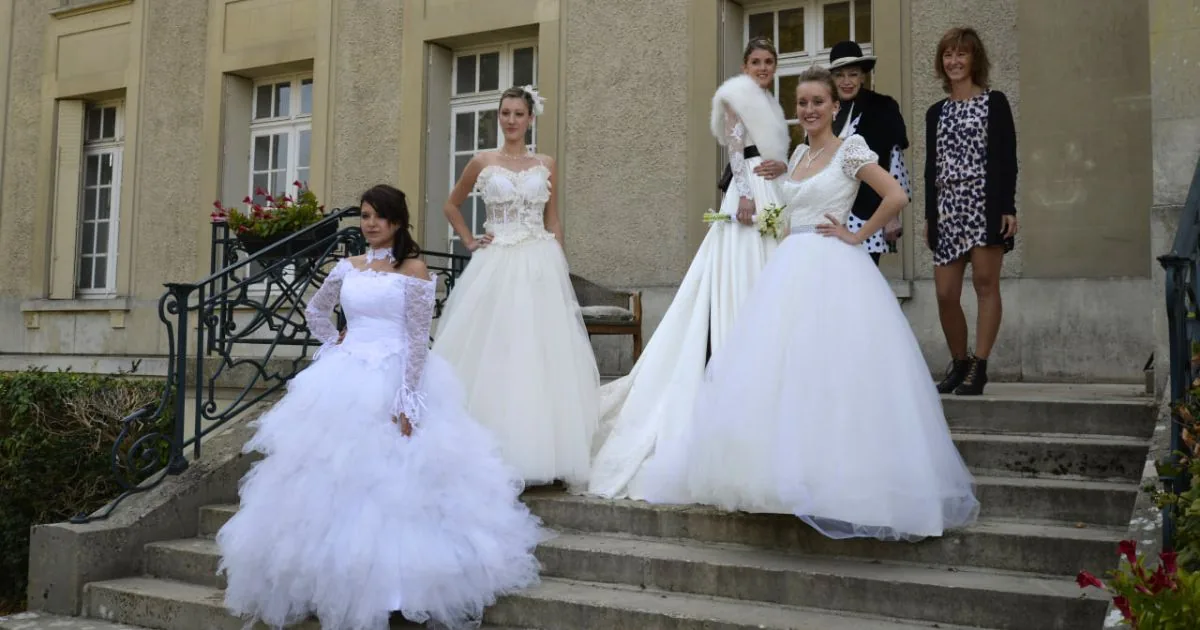Femmes en robes de mariée blanches à manches en dentelle et jupes en tulle sur un escalier en pierre.