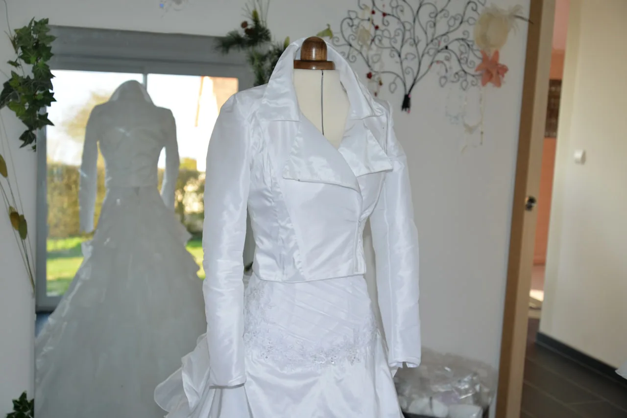 Tenue de mariée ivoire sur mannequin de couture : veste courte à col tailleur en satin et broderie perlée