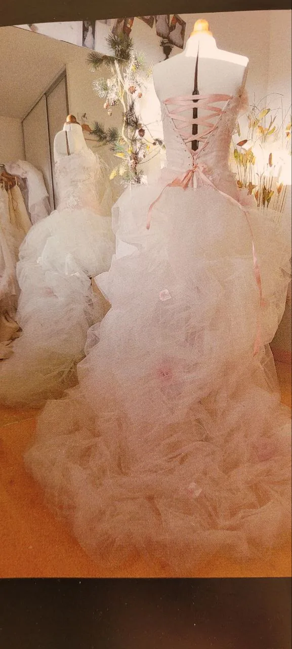 Robe de mariée de dos en tulle sur mannequin, laçage corset à ruban rose et volants plissés