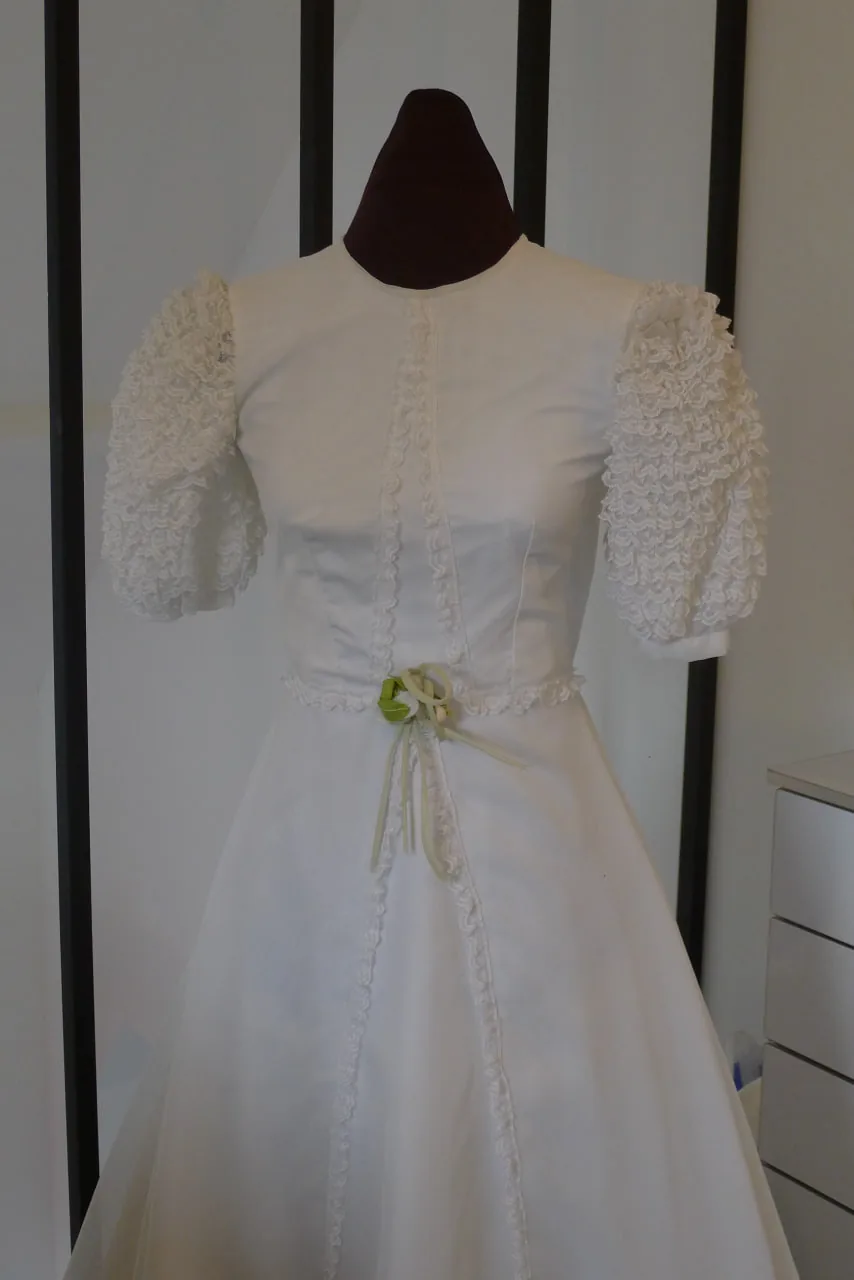 Robe de mariée blanche sur mannequin de couture : ligne A, manches courtes bouffantes, ruban vert à la taille