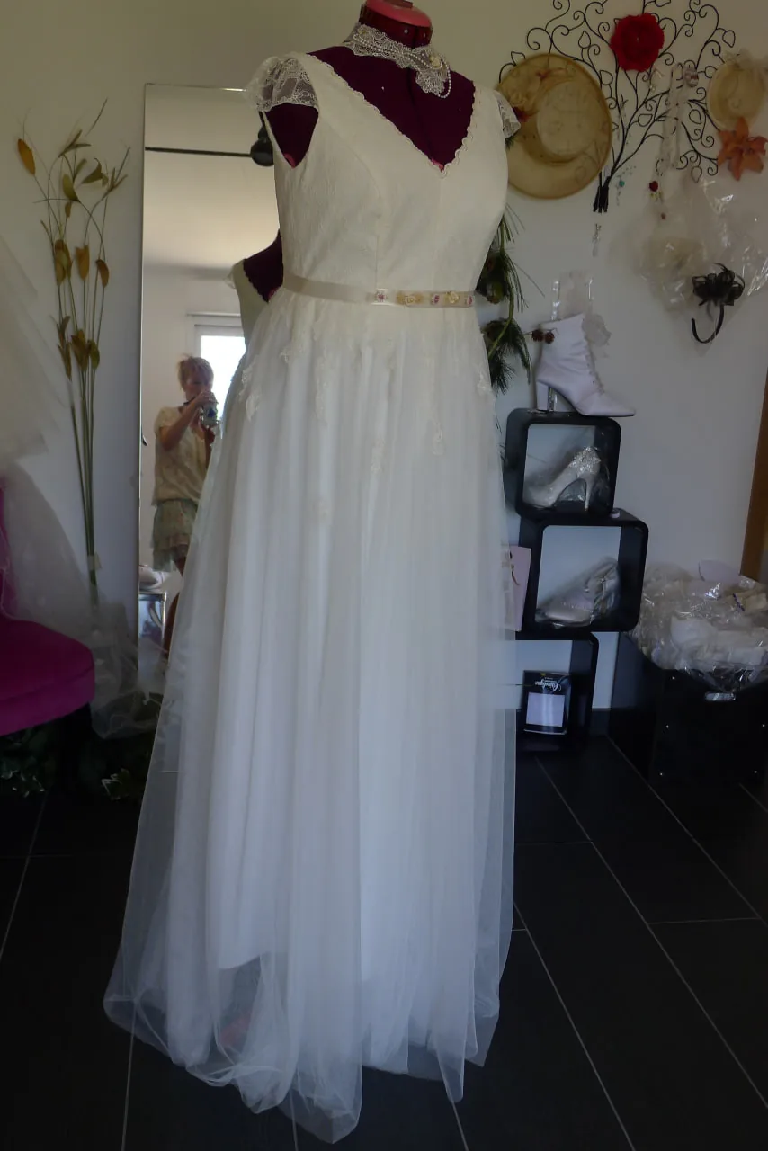 Robe de mariée ligne A ivoire sur mannequin : encolure V dentelée, ceinture fine et jupe en tulle à appliques